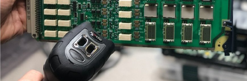 Someone using a handheld barcode scanner against a circuit board