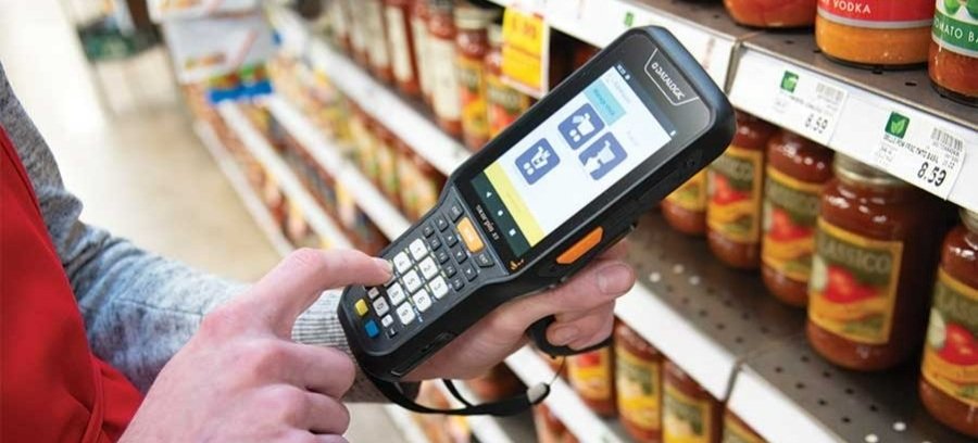 A handheld Datalogic barcode scanner being used in a retail store