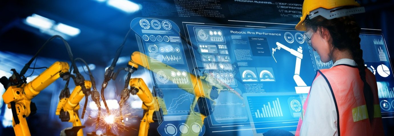 A man reviewing analytics on a hologram as robotic arms work to manufacture something