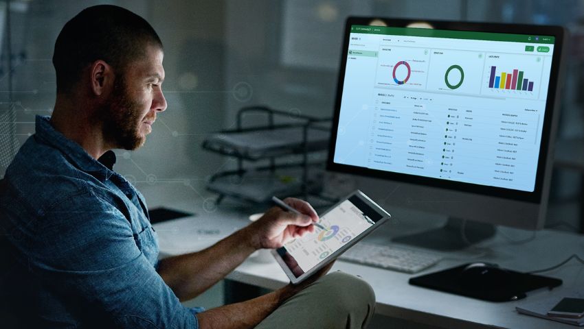 A man using a tablet in front of a computer