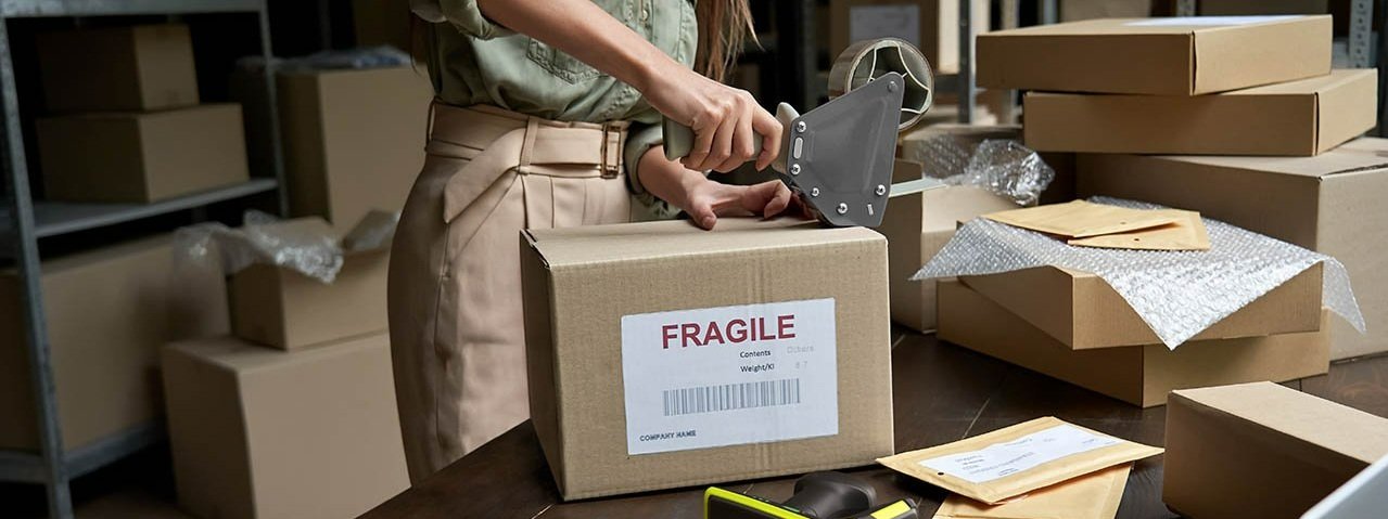 A woman sealing a box with tape