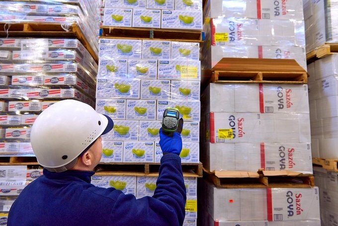 A man using a handheld barcode scanner to scan various packages