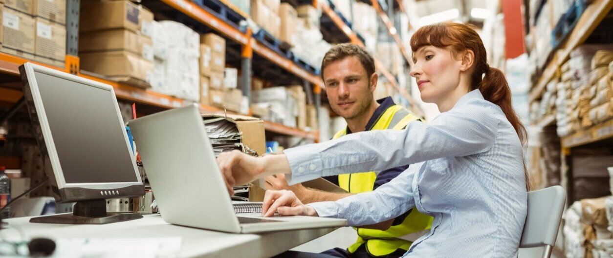 Two people working on a laptop in a warehouse