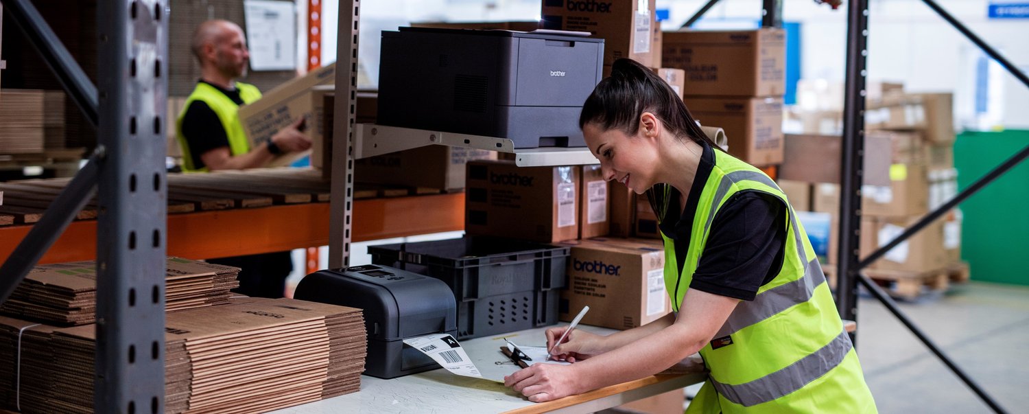 A woman by a barcode printer in a warehouse