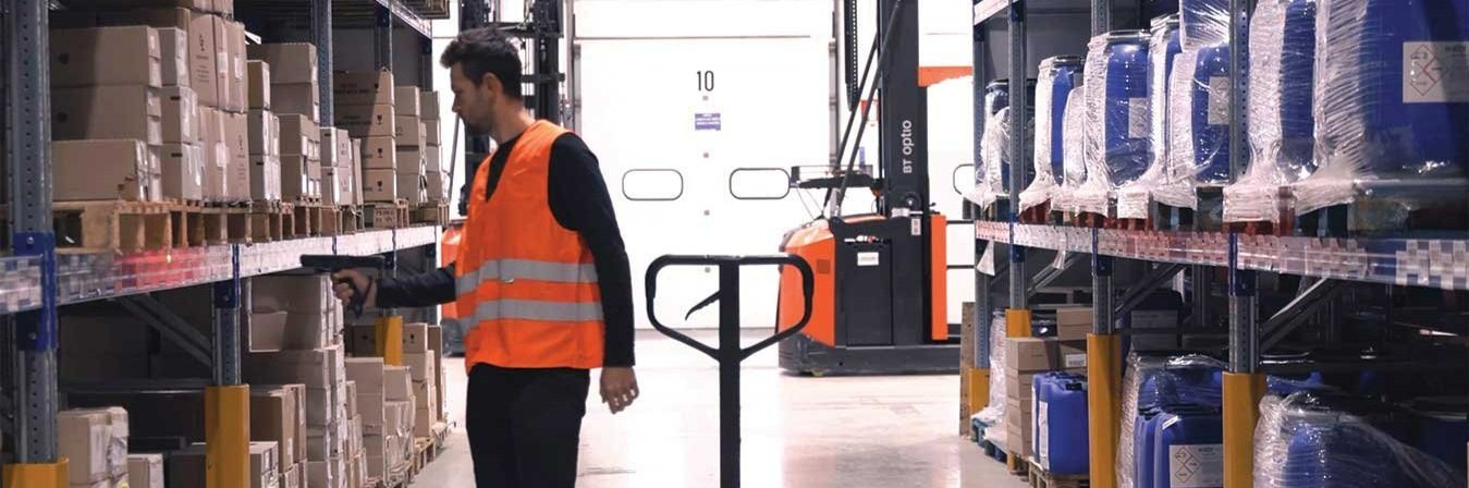A man using a handheld barcode scanner on packages in a warehouse