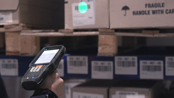 Someone using a handheld barcode scanner in a warehouse