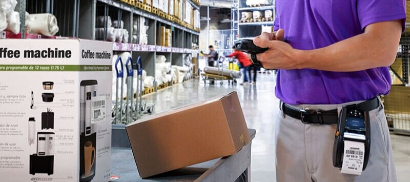 Someone using a barcode scanner and mobile printer for a package in a warehouse