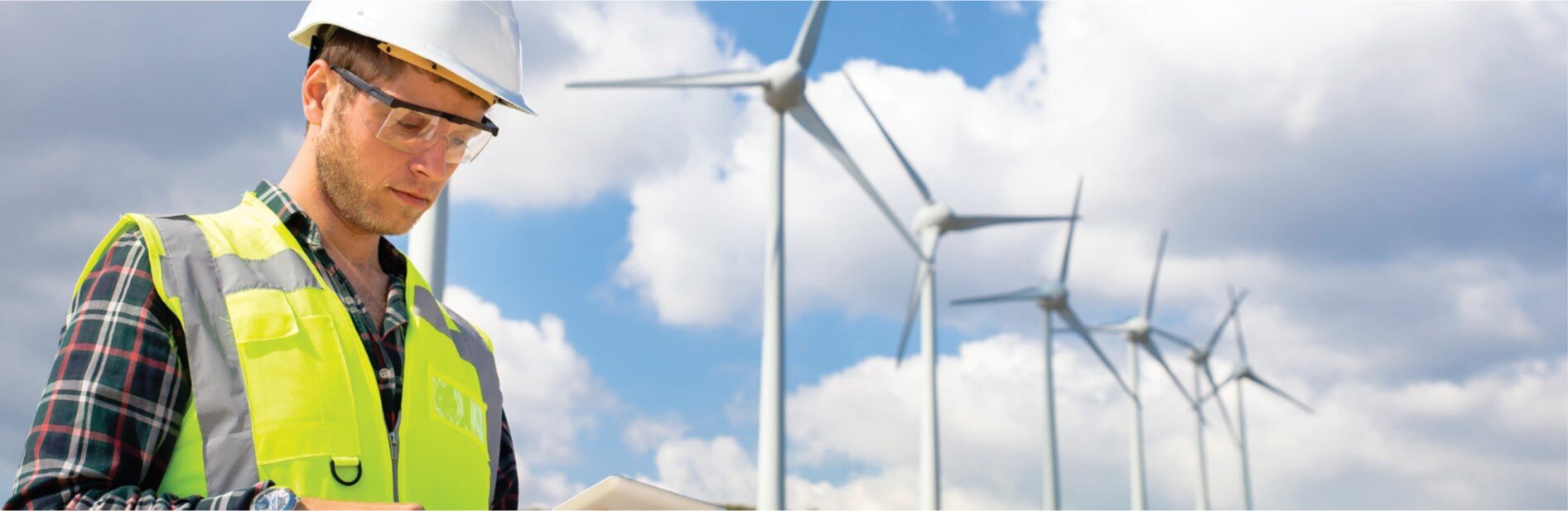 A man looking at a tablet with windmills in the background