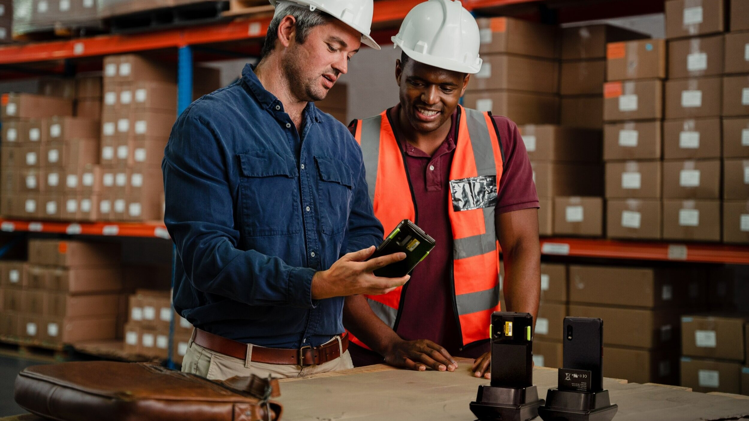 Two workers in a warehouse looking at a mobile computer