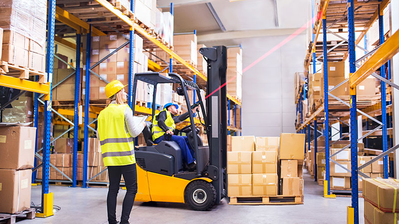 A warehouse worker using an extended range barcode scanner from a forklift