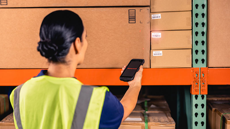 A worker using an ultra-rugged Honeywell mobile computer in a warehouse