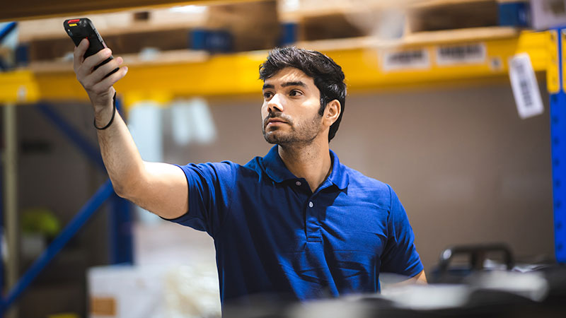 A man using a mobile device in the warehouse