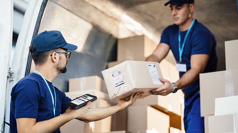 A delivery person scanning a package with a mobile computer