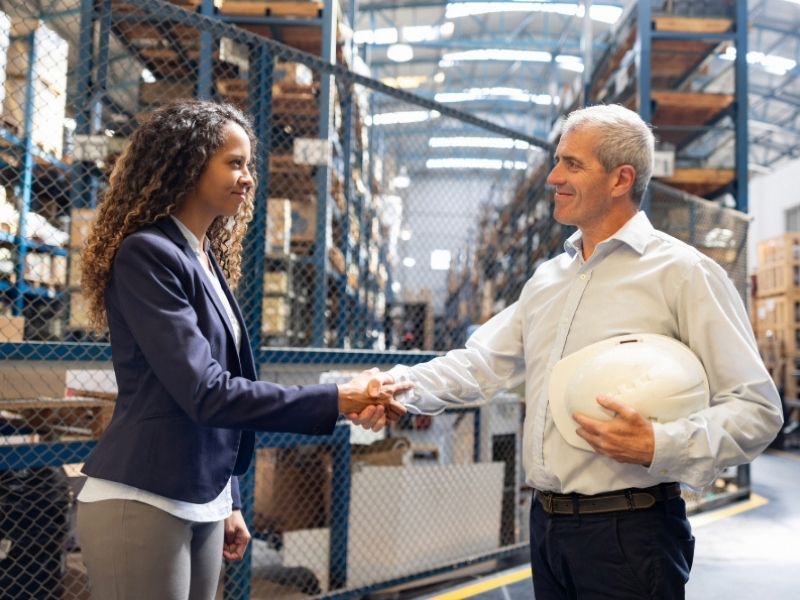 Two people shaking hands in a warehouse