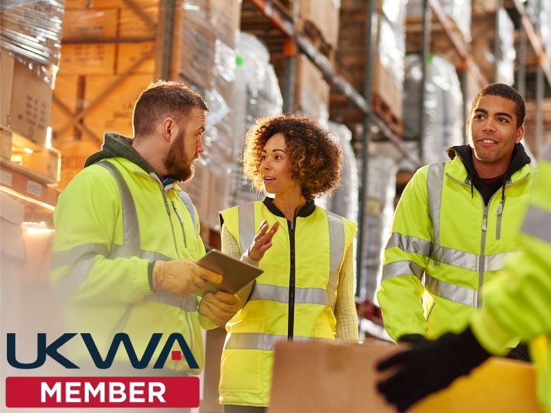 A group of warehouse employees with the UKWA logo overlayed