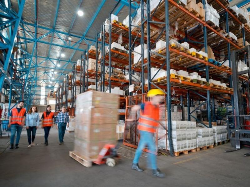 Worker transporting boxes in warehouse.