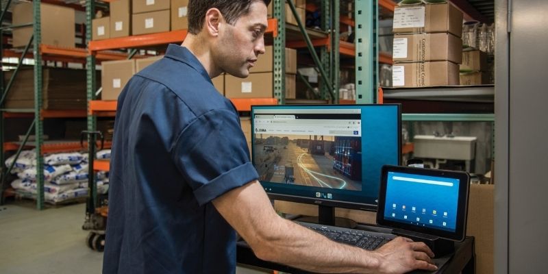 A man in a warehouse using a device