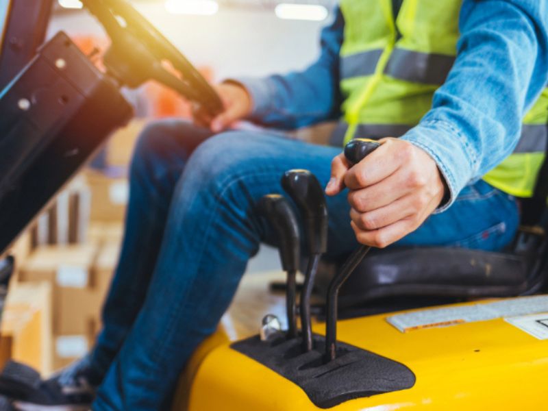 Someone using a forklifts gear stick.