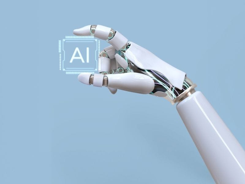 A robotic arm holding a icon with AI on it